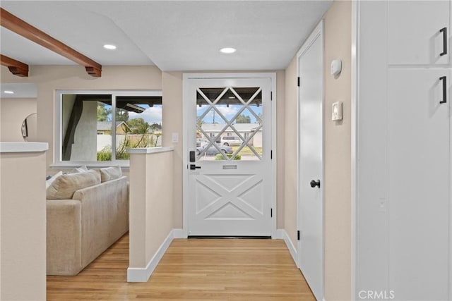 entryway with light wood finished floors, recessed lighting, beam ceiling, and baseboards
