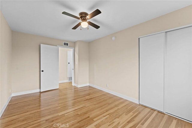 unfurnished bedroom featuring light wood finished floors, a closet, ceiling fan, visible vents, and baseboards
