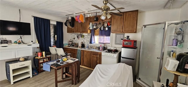 kitchen featuring a sink, white range with gas stovetop, light wood-type flooring, a ceiling fan, and freestanding refrigerator