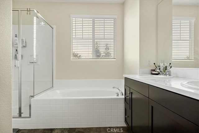 bathroom featuring a garden tub, a stall shower, double vanity, and a sink