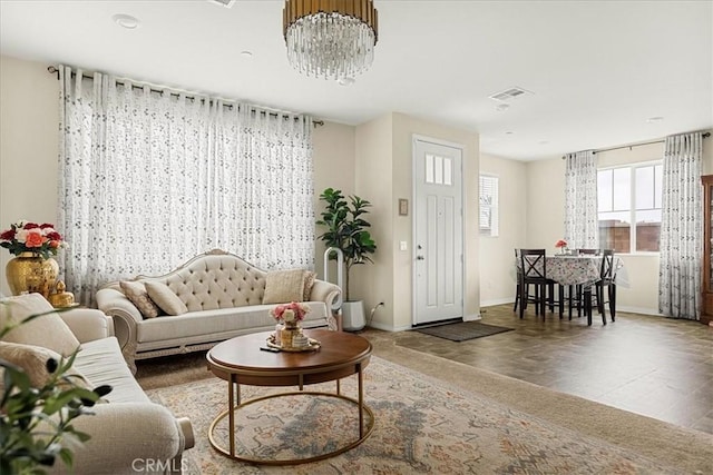 living room with baseboards, visible vents, and a notable chandelier