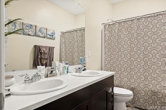 full bath with toilet, double vanity, and a sink