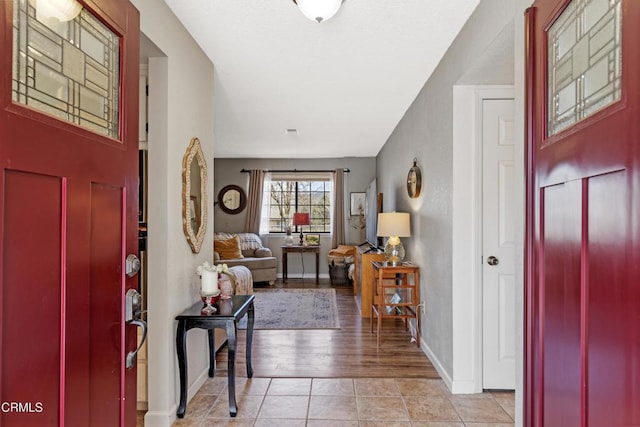 entryway with light tile patterned flooring and baseboards