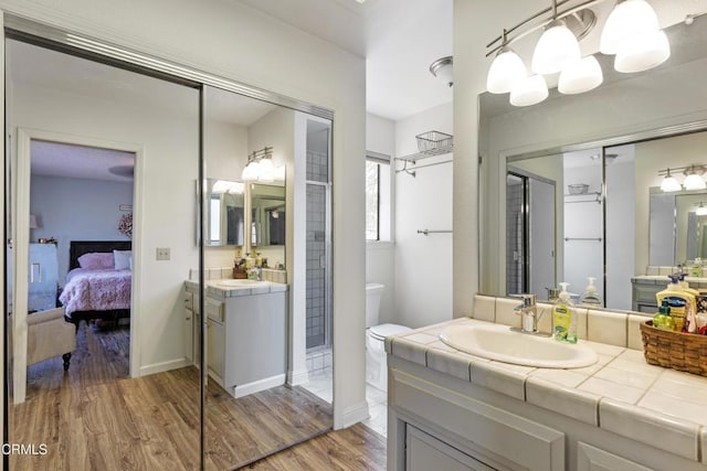 full bathroom with wood finished floors, ensuite bath, two vanities, toilet, and a sink