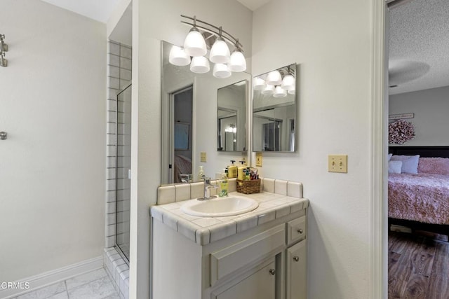 ensuite bathroom with walk in shower, vanity, ensuite bath, and baseboards