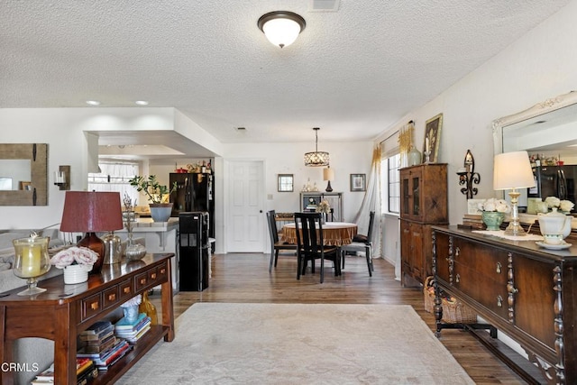 interior space with a textured ceiling, visible vents, and wood finished floors