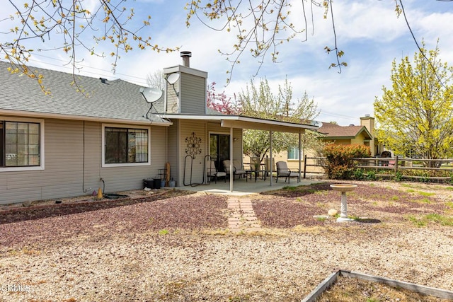 rear view of property with fence, a chimney, a shingled roof, and a patio