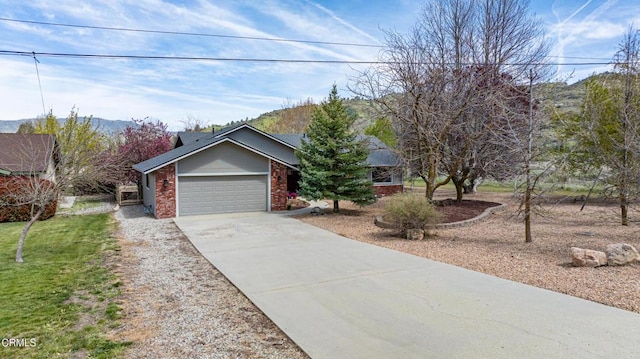 single story home featuring a front lawn, a garage, a mountain view, brick siding, and concrete driveway
