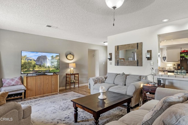 living room with visible vents, wood finished floors, and a textured ceiling