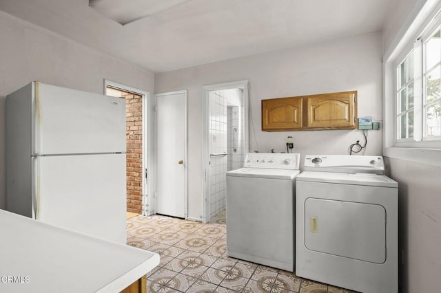 washroom featuring light tile patterned flooring, separate washer and dryer, and cabinet space