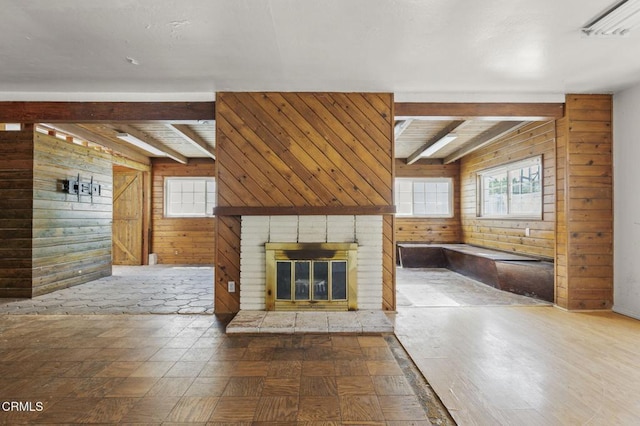 unfurnished living room featuring beam ceiling, wood walls, and a fireplace