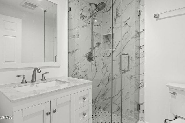 bathroom featuring vanity, toilet, visible vents, and a marble finish shower