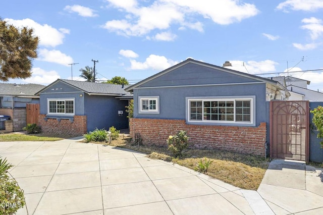 view of front facade with brick siding, fence, stucco siding, and a gate