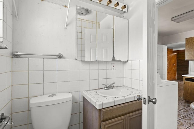 bathroom with toilet, vanity, tasteful backsplash, and washer / clothes dryer