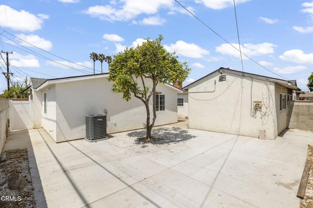 rear view of house with fence, a patio area, cooling unit, and stucco siding