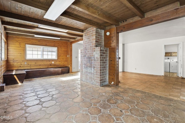 unfurnished living room with independent washer and dryer, beam ceiling, stone floors, wood walls, and wood ceiling