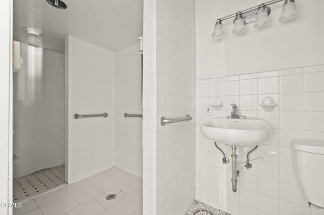 bathroom featuring tile walls, toilet, a tile shower, and tile patterned flooring