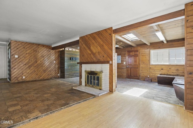 unfurnished living room with wood finished floors, a healthy amount of sunlight, wooden walls, and a fireplace