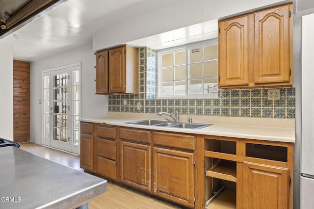 kitchen with brown cabinets, decorative backsplash, light countertops, and a sink