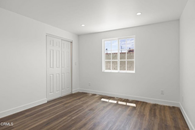 unfurnished bedroom featuring dark wood-type flooring, a closet, recessed lighting, and baseboards