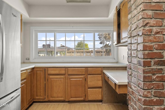 interior space featuring brown cabinets, light countertops, light wood-style flooring, and freestanding refrigerator