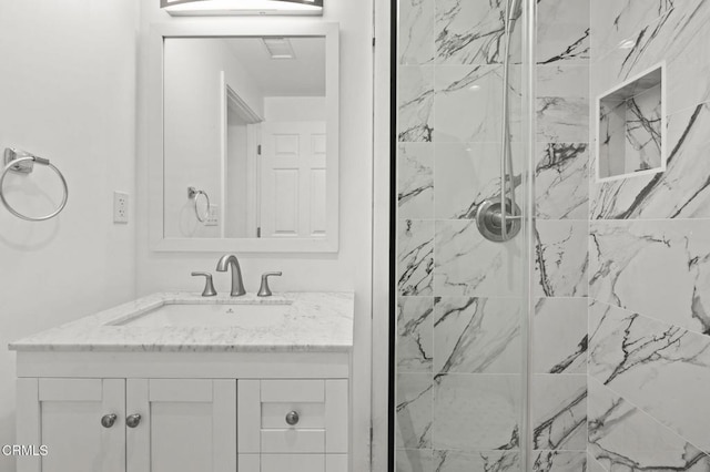 bathroom featuring a marble finish shower and vanity