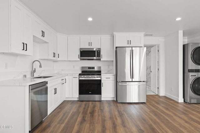 kitchen with stacked washer / drying machine, recessed lighting, a sink, stainless steel appliances, and white cabinetry