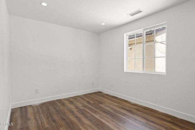 empty room featuring visible vents, dark wood finished floors, and baseboards