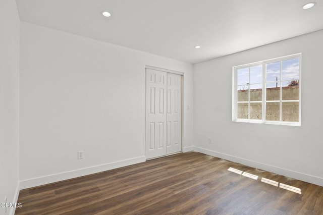 empty room featuring dark wood finished floors, baseboards, and recessed lighting
