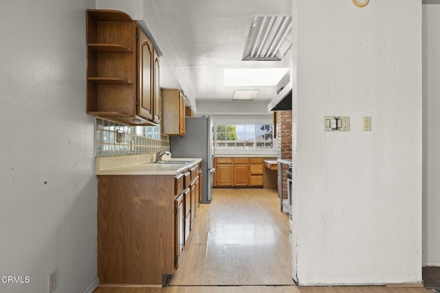 kitchen featuring brown cabinets, light wood finished floors, a sink, and open shelves