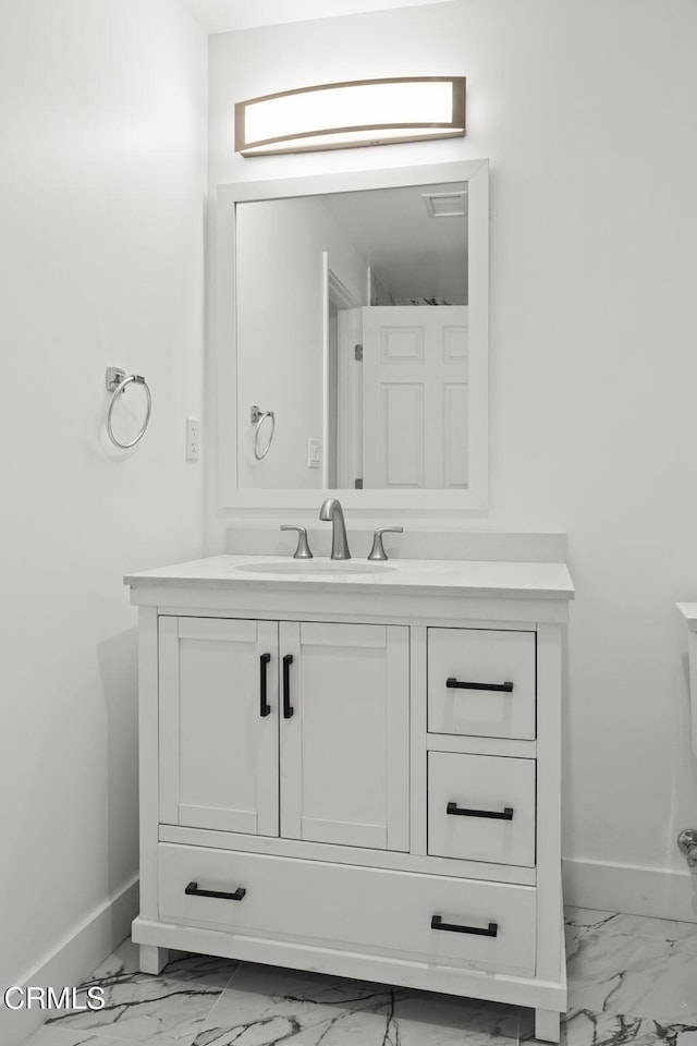 bathroom with baseboards, vanity, and marble finish floor