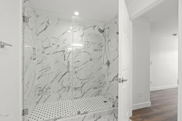 bathroom with recessed lighting, a marble finish shower, wood finished floors, and baseboards