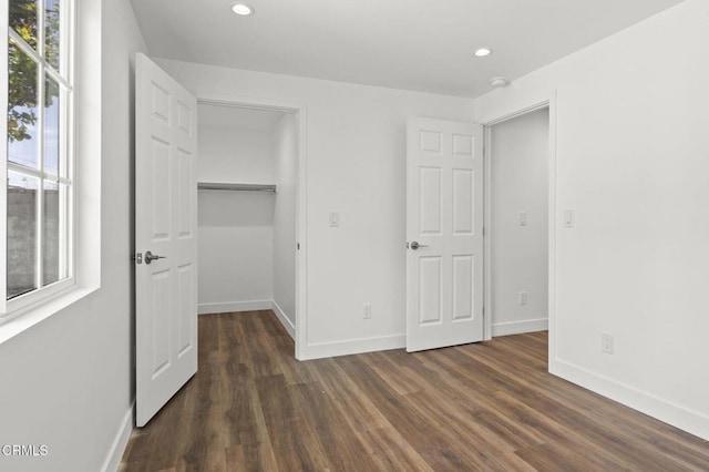 unfurnished bedroom featuring recessed lighting, baseboards, a spacious closet, and dark wood finished floors
