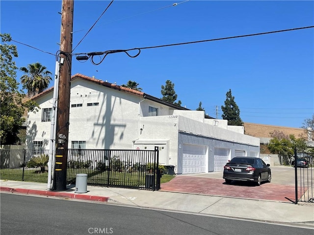 13252 Newland St A-D, Unit A-D Garden Grove, CA 92844 - view of side of home featuring an attached garage, stucco siding, driveway, and fence