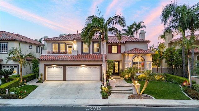 mediterranean / spanish-style house with an attached garage, driveway, a chimney, and stucco siding