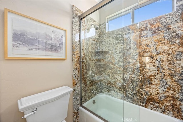 bathroom featuring toilet and bath / shower combo with glass door