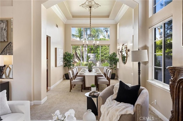 interior space featuring an inviting chandelier, ornamental molding, carpet floors, a towering ceiling, and baseboards