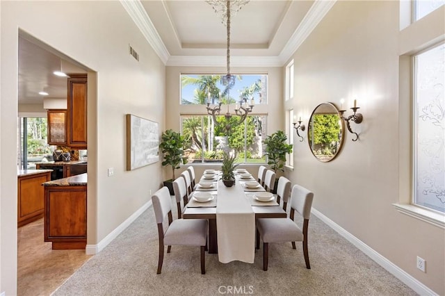 dining room featuring an inviting chandelier, a towering ceiling, a tray ceiling, and visible vents