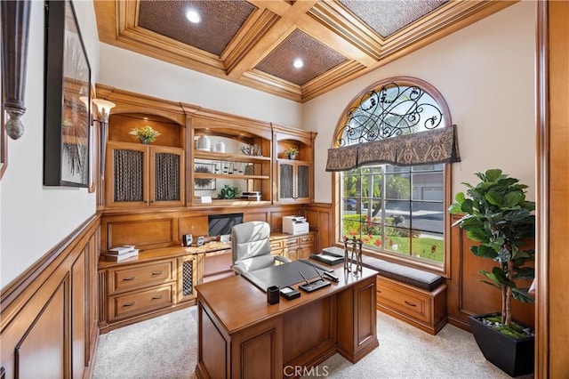 office area featuring light colored carpet, crown molding, wainscoting, built in desk, and coffered ceiling