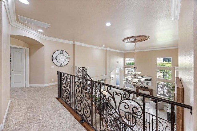 corridor featuring crown molding, arched walkways, an upstairs landing, and visible vents