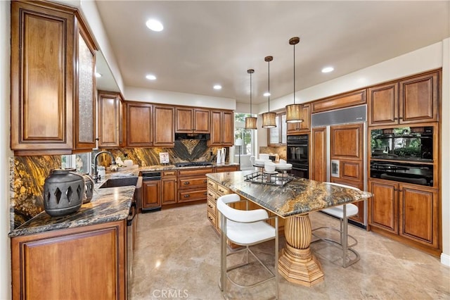 kitchen featuring a center island, brown cabinets, gas stovetop, a sink, and paneled fridge