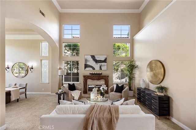 living area featuring visible vents, arched walkways, baseboards, a high ceiling, and carpet