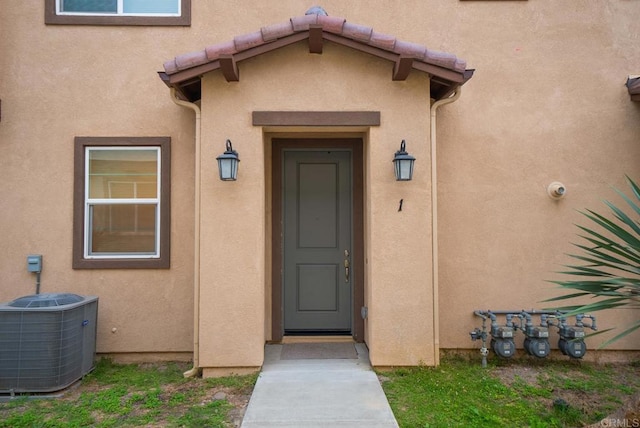 entrance to property featuring stucco siding and central AC unit