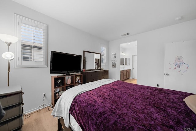 bedroom with visible vents, ensuite bathroom, and light wood finished floors