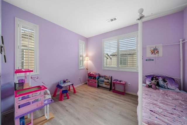 bedroom with visible vents, wood finished floors, and baseboards