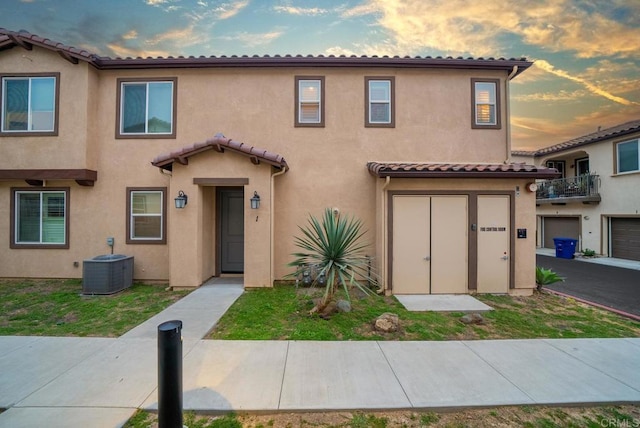 view of front of home with stucco siding, central air condition unit, and a tile roof