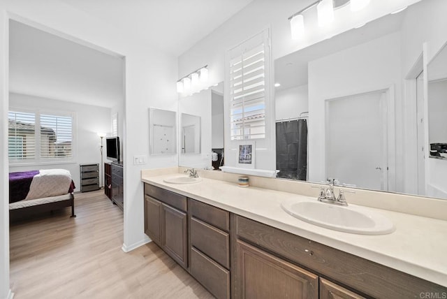 ensuite bathroom featuring double vanity, a sink, wood finished floors, and ensuite bathroom