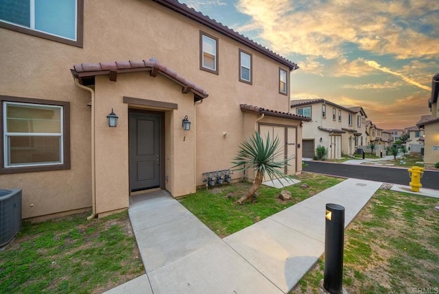exterior space featuring central AC, stucco siding, a tile roof, and a residential view