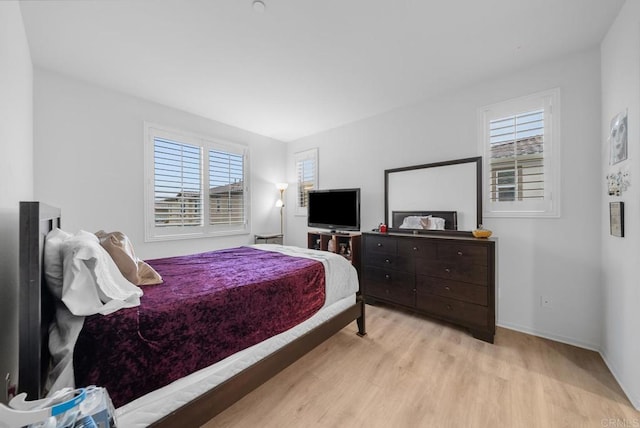 bedroom with wood finished floors, baseboards, and multiple windows