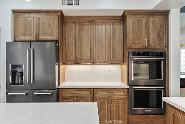 35183 Flamingo Way, Winchester, CA 92596 - kitchen featuring high end fridge, double oven, light countertops, and brown cabinetry